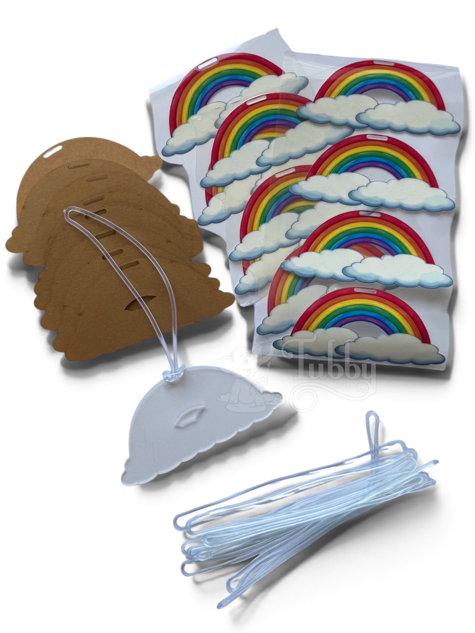 Pack of 10 clear rainbow-shaped acrylic luggage tag blanks with paper backing film, 10 colorful rainbow UV waterproof stickers, and clear silicone attachment loops laid out on a white surface.